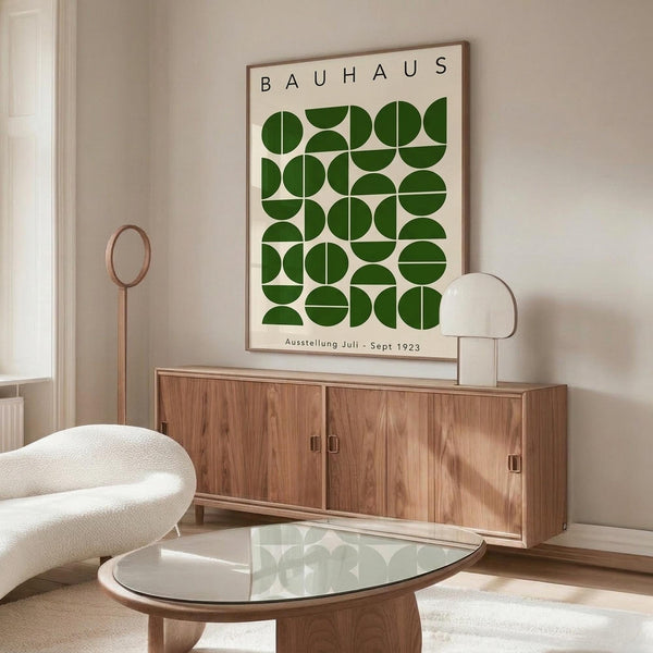 May include: Framed Bauhaus exhibition poster with green geometric circles and semicircles arranged in a grid pattern, displayed above a wooden sideboard in a minimalist living room with white curved chair, glass coffee table, and modern lamp