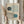 May include: Person in beige clothing holding framed Bauhaus poster with geometric design featuring two circles in dark green and teal blue connected by curved linear patterns on cream background, displayed next to dried pampas grass in soft natural lighting