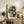May include: Abstract geometric artwork in mustard yellow, navy blue, gray and cream tones displayed in light wood frame on rustic wooden sideboard. Modern art print features curved and angular shapes in contemporary style. Room scene shows neutral armchair, fern plant, ceramic vase, and stacked books creating warm, minimalist home decor setting with natural lighting.