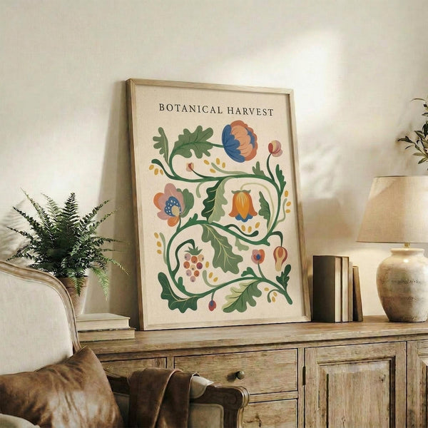 May include: Framed botanical poster with decorative floral design featuring colorful stylized flowers, leaves, and vines in orange, blue, and green tones on cream background. Display shows rustic wooden sideboard with books, ceramic vases, fern plant, and neutral-toned living room setting with beige sofa and pillows.