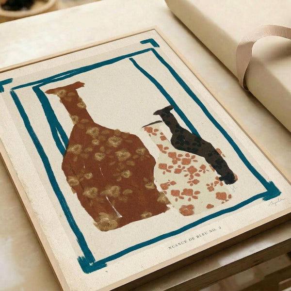 Abstract art print featuring silhouettes of two ceramic vessels - a brown pitcher with golden circular patterns and a white vase with rust-colored spots. The vessels are rendered in earthy tones against a cream background, surrounded by a hand-painted teal border frame. The artwork sits on white paper in an open art book or portfolio, with white ribbon visible at the edge, creating an elegant studio presentation.