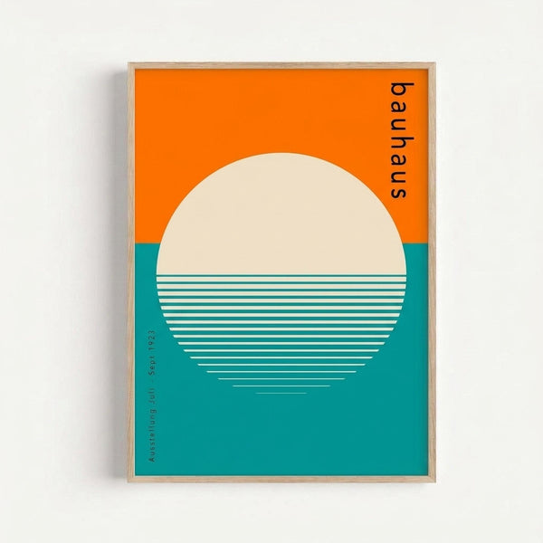 A minimalist geometric poster featuring a large cream circle against an orange sky and teal water, with white horizontal lines creating a reflection effect across the lower half of the circle. The design uses a retro color palette and includes vertical text reading "bauhaus" along the right edge. The artwork is displayed in a simple wooden frame against a white wall.