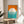 May include: Framed Bauhaus-style poster with geometric design featuring large white circle overlapping orange and teal sections with horizontal white stripes, displayed on round wooden side table next to beige upholstered chair, with plant leaves visible and natural window light creating shadows on white wall