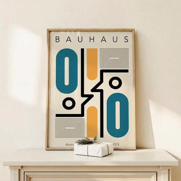 May include: Bauhaus-style poster print in light wood frame displaying abstract geometric shapes in teal and orange with black lines and concentric rectangles, displayed on white wooden console table next to small wrapped gift with botanical sprig against cream wall