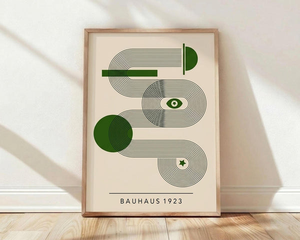 May include: Framed geometric art print with curved flowing lines in black and green on cream background, displayed in light wood frame against white wall on wooden floor with soft natural lighting and fabric shadows