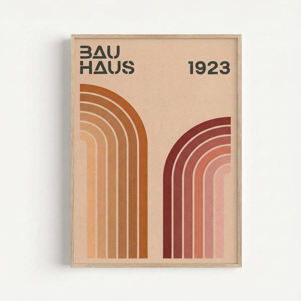 Framed poster with cream background featuring two geometric rainbow arches in earth tones. Left arch displays warm orange and brown curved stripes, right arch shows burgundy to pink gradient stripes. Black text reads "BAUHAUS" and "1923" at top. Minimalist design with clean lines and muted color palette, displayed against white wall in light wood frame.