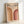 May include: Framed vintage-style poster with beige background featuring "BAUHAUS 1923" text and two curved rainbow arches in warm orange and burgundy tones. The minimalist geometric design sits in a light wood frame, leaning against a white wall on what appears to be a light surface.