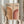 May include: Person in beige clothing holding framed Bauhaus poster featuring two geometric rainbow arches in orange and burgundy tones on cream background, displayed against neutral wall with dried pampas grass stems visible to the left side.