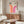 May include: Modern living room with Bauhaus-inspired poster featuring orange and pink curved geometric shapes and "1923" text, displayed above walnut sideboard. White sculptural chair and glass coffee table complete the mid-century modern setting with neutral walls and natural lighting.