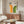May include: Bauhaus-inspired geometric poster with orange and green rainbow arches on cream background, displayed above mid-century walnut credenza in minimalist living room with white curved chair, glass coffee table, and modern table lamp