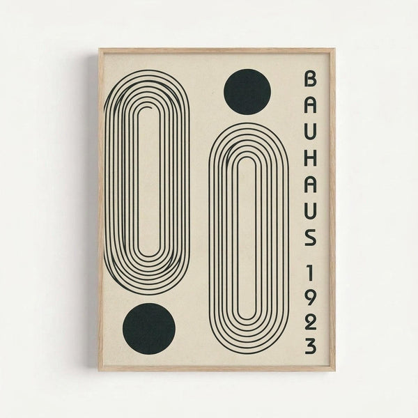 Framed minimalist poster with cream background featuring two large black outlined oval shapes with concentric lines, two solid dark green circles, and vertical text reading "BAUHAUS 1923" on the right side. The geometric design has a modernist aesthetic with clean lines and simple shapes in a light wood frame against a white wall.