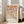 May include: Framed geometric poster with gradient circles and semicircles in warm terracotta, peach, tan, and gray tones arranged in a grid pattern, displayed on light wood floor next to beige sofa in bright living room with white walls and large windows