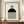 May include: Framed Bauhaus-style poster with geometric black semicircle, concentric circle pattern, and vertical black and white stripes on cream background. Displayed on wooden sideboard next to white ceramic vase and books in elegant room with white paneled walls.