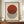 May include: Framed Bauhaus exhibition poster with red circle overlapping black and white striped circle on cream background, displayed on wooden sideboard next to white ceramic vase and books in room with white walls and molding