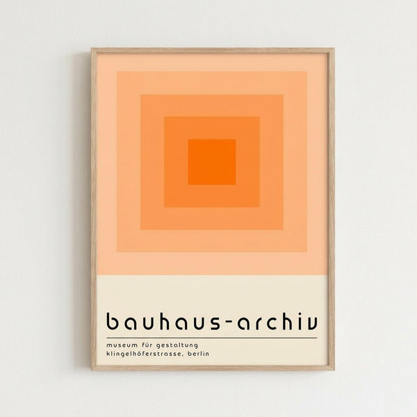 A framed poster featuring concentric orange squares in graduating shades from bright orange in the center to pale peach at the edges, displayed against a white wall. The artwork has "bauhaus-archiv" text below with "museum für gestaltung klingelhöferstrasse, berlin" in smaller print. The poster is mounted in a light wood frame with clean geometric design typical of Bauhaus style.