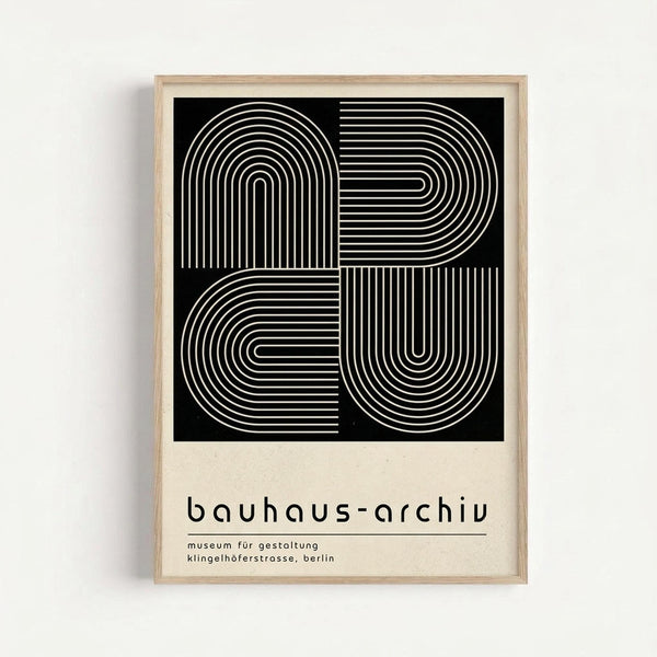 Framed minimalist poster with black square containing white geometric line art forming interlocking curved and angular patterns. Below the artwork, text reads "bauhaus-archiv" and "museum für gestaltung klingelhöferstrasse, berlin" in lowercase sans-serif font on cream-colored background. Light wood frame against white wall.
