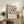 May include: Framed geometric art print with colorful circles and semicircles in pink, blue, orange, and green displayed on rustic wooden sideboard. Room setting features neutral armchair, potted fern, ceramic vases, and stacked books creating modern minimalist home decor scene with warm natural lighting.