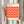 May include: Person in beige sweater holding framed geometric poster with pink and orange diamond cube pattern. Black text reads "bauhaus ausstellung" at top and "WEIMAR JULI-SEPT 1923" at bottom. Light wood frame, neutral background with dried wheat stems visible on left side.