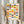 May include: Person holding framed Bauhaus-style poster featuring geometric pattern of colorful half-circles in rows. Circles show vibrant colors including yellow, orange, coral, teal, blue, and sage green on cream background. Light wood frame, neutral interior setting with dried pampas grass visible. Hands wearing beige long-sleeved top with gathered cuffs.