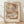 May include: Framed abstract art print with overlapping geometric circles and curved shapes in warm earth tones including terracotta, sage green, cream, and soft browns. The minimalist composition features translucent layered forms creating depth and movement. Displayed in light wood frame against white textured wall on wooden floor with natural sunlight casting diagonal shadows across the scene.