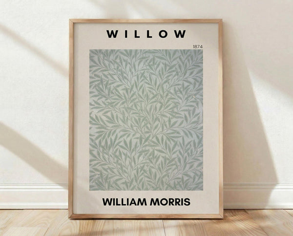 May include: Framed botanical poster print featuring intricate sage green willow leaf pattern on cream background, displayed in light wood frame against white textured wall on natural wood flooring with soft natural lighting and shadows