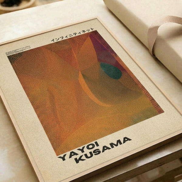 May include: Abstract art print with warm orange, brown, and green curved shapes on textured dotted background, displayed in white mat frame on neutral surface with white ceramic vase. Features Japanese text at top and "YAYOI KUSAMA" at bottom in black letters.
