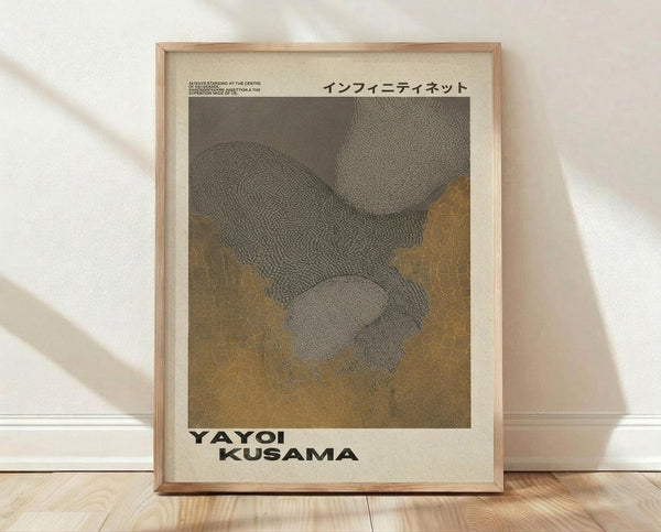 May include: Framed art print leaning against white wall on light wood floor. Poster features abstract interwoven forms in gray and golden yellow with intricate dotted textures. Japanese text appears at top, artist name at bottom. Natural wood frame with cream matting. Soft shadows cast across white textured wall.