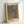 May include: Framed art print leaning against white wall corner showing abstract dotted pattern in gray and golden yellow tones. Japanese text at top, artist name at bottom. Natural wood frame with white matting. Textured dotted design creates flowing, organic shapes across the composition.
