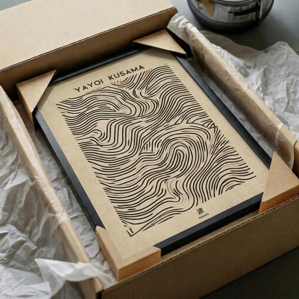 May include: Abstract art print with flowing black linear waves pattern on cream paper, displayed in black frame inside cardboard shipping box with white tissue paper. Wooden dowels and glass vessel visible nearby. Minimalist topographic-style design with organic curved lines creating undulating surface effect.