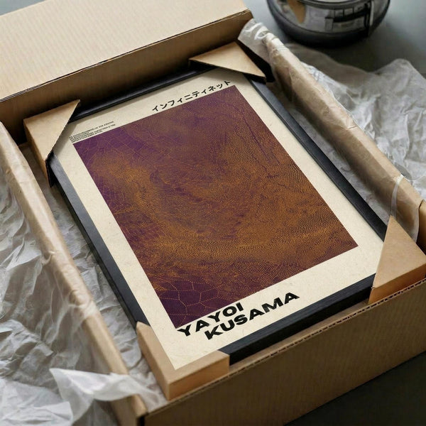 May include: Framed art print with purple and brown dotted pattern in minimalist style, displayed in wooden frame inside cardboard packaging with tissue paper and wooden dowels, sitting on white surface next to dark glass object