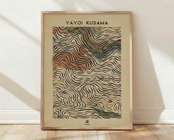 May include: Framed art print with flowing, wavy line patterns in earth tones of brown, beige, orange, and muted colors on textured beige background. Text reads "YAYOI KUSAMA" at top and Japanese character with "waves" at bottom. Light wooden frame sits on wooden floor against white wall with soft natural lighting and fabric shadows.