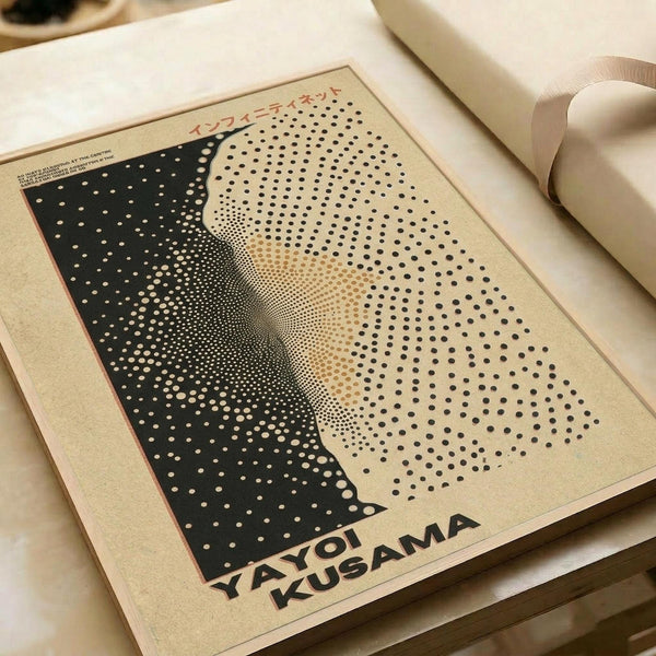 A beige art print featuring a halftone dot portrait of a woman's face in black and cream tones, with "YAYOI KUSAMA" text at the bottom and Japanese characters at the top. The poster lies flat on white paper with a cream ribbon visible in the corner, showing the minimalist dotted pattern artwork inspired by the artist's signature infinity net style.