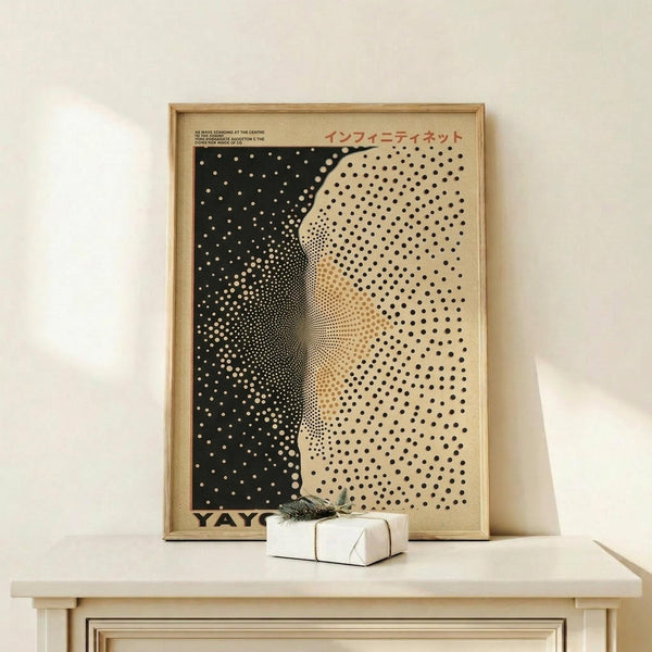 May include: Abstract art print in wooden frame showing black and cream halftone dot pattern creating curved, flowing forms. Japanese text visible at top. Print sits on light wood surface next to small wrapped white gift box with green sprig. Minimalist display against neutral wall with natural lighting.