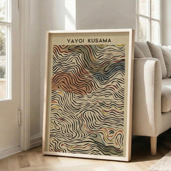 May include: Large framed abstract poster with flowing wavy lines in earth tones of beige, brown, orange and muted colors, leaning against white wall next to beige upholstered chair in bright living room with tall windows and natural light casting shadows on wooden floor.