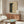 May include: Framed poster with black and cream polka dot pattern creating curved optical illusion effect, displayed above wooden sideboard in modern living room setting with white curved chair, oval glass coffee table, and floor lamp. Neutral beige walls with natural lighting.