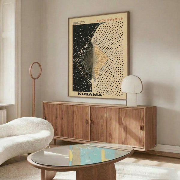 May include: Framed poster with black and cream polka dot pattern creating curved optical illusion effect, displayed above wooden sideboard in modern living room setting with white curved chair, oval glass coffee table, and floor lamp. Neutral beige walls with natural lighting.
