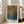 May include: A framed art print leaning against a white wall next to a beige sofa in a bright room with large windows. The poster features an abstract composition of golden yellow and deep blue dotted patterns that appear to flow and merge together. Text reading "YAYOI KUSAMA" appears at the bottom along with "Tokyo 1998" and Japanese characters at the top. The artwork is displayed in a natural wood frame on light wooden flooring.