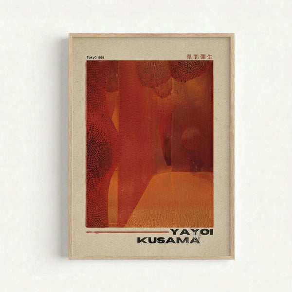 A framed art poster featuring abstract orange and red tones with dotted halftone patterns creating geometric shapes and forms. The artwork has a warm, textured appearance with overlapping translucent elements. Text reading "TOKYO 1998" appears in the upper left, Japanese characters in the upper right, and "YAYOI KUSAMA" in bold black letters at the bottom. The poster is displayed in a light wooden frame with cream matting against a white wall.