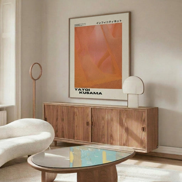 May include: Orange and pink dotted abstract art poster with Japanese text displayed above a wooden sideboard in a minimalist living room setting with white curved chair, glass coffee table, and modern lighting fixtures against cream walls