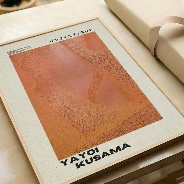 May include: Orange and coral colored abstract art print with dotted halftone pattern creating flowing organic shapes, displayed in white matted frame on neutral surface beside rolled paper tube. The artwork features warm gradient tones from peachy pink to deep orange with stippled texture throughout.