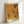 May include: Framed poster with yellow and orange dotted pattern artwork leaning against white wall. The print features Kusama's signature polka dot style in warm golden tones with organic flowing shapes. Black text at bottom reads "YAYOI KUSAMA" with "TOKYO 1998" in upper corner. Light wooden frame surrounds the contemporary art print in minimalist room setting.
