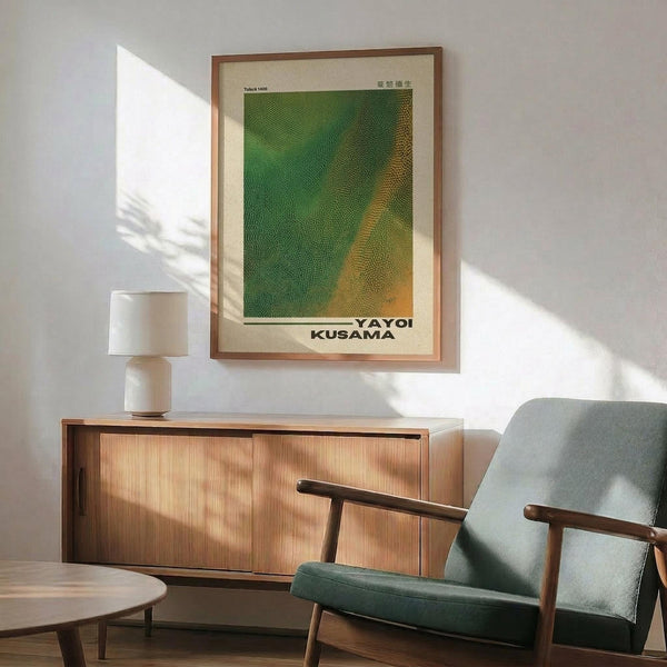 May include: Modern living room with green and orange abstract dotted art print in wooden frame hanging above walnut credenza. White ceramic table lamp sits on sideboard next to mid-century sage green upholstered armchair with wooden arms. Dramatic window light creates geometric shadows across white walls and round wooden coffee table.