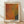 May include: Framed art print featuring abstract organic shapes in warm orange, yellow, and dark blue-green tones with halftone dot pattern texture. Text reads "Tokyo 1998" and "YAYOI KUSAMA" with Japanese characters. Light wood frame displayed against white wall on wooden floor with natural lighting creating soft shadows.