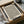 May include: Framed beige poster with black polka dot pattern in halftone style, displayed in black frame inside cardboard shipping box with protective tissue paper. Wooden dowels visible alongside for hanging. Clean minimalist design with dense dots creating gradient effect from top to bottom.