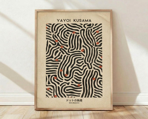 May include: Framed art print with black flowing organic lines and small red dots on cream background, displayed in light wood frame against white wall on wooden floor with soft natural lighting and shadows