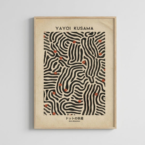 May include: Framed art print hanging on white wall featuring abstract black wavy lines with small red-orange dots scattered throughout on cream background. Text reads "YAYOI KUSAMA" at top and Japanese characters with "dots obsession" at bottom. Light wood frame with natural grain visible.