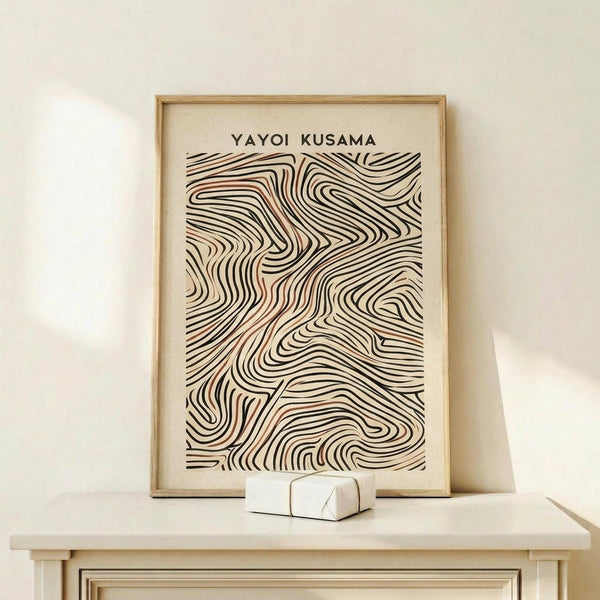 May include: Framed poster with abstract flowing wave-like lines in black and terracotta orange on cream background, displayed on light wood surface against white wall. Small white geometric object sits in front of the natural wood frame. The swirling linear pattern creates an organic, hypnotic design reminiscent of topographical maps or flowing water.