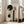 May include: Large framed abstract art print leaning against white wall next to beige armchair in bright living room. Artwork features geometric black circles, vertical rectangular shapes, and silhouetted tree forms in monochromatic palette on textured beige background with natural wood frame.
