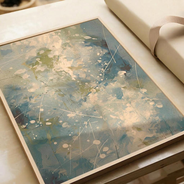 Abstract expressionist artwork featuring splattered paint in muted blue, green, and cream tones with white geometric lines creating an interconnected web pattern across the composition. The print is displayed on white paper with soft lighting and a cream ribbon visible in the upper right corner.