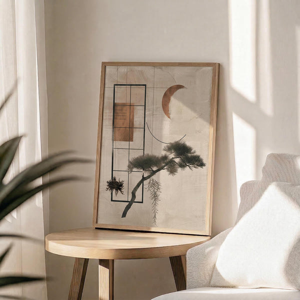 May include: Framed abstract art print displayed on round wooden side table next to beige upholstered chair. Artwork features geometric shapes, crescent moon, and stylized pine tree branch in neutral earth tones. Natural lighting creates soft shadows across cream-colored wall. Green plant leaves visible in corner of minimalist room setting.